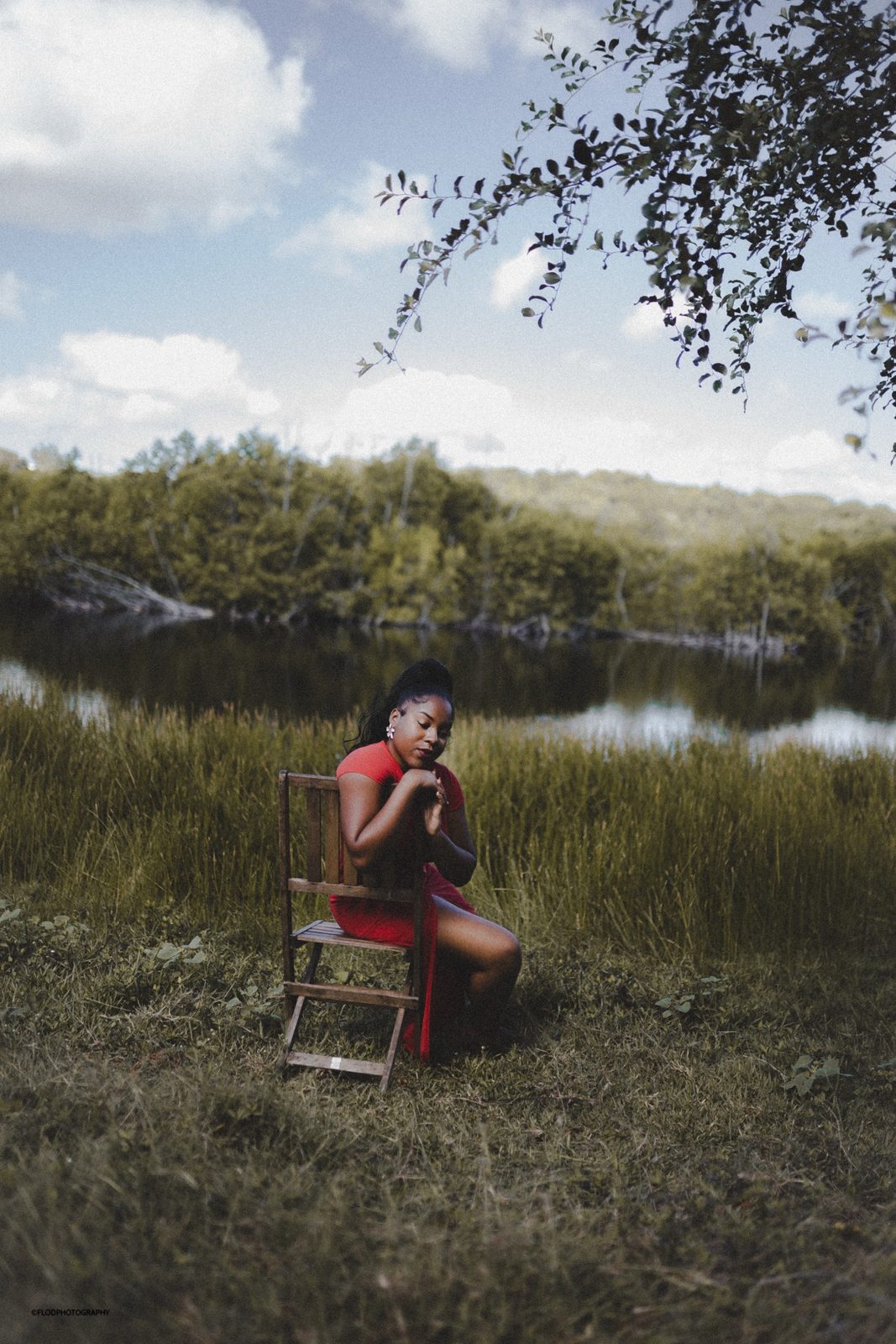 Portrait en extérieur, robe rouge sur chaise en bois au bord de l'eau, Guadeloupe