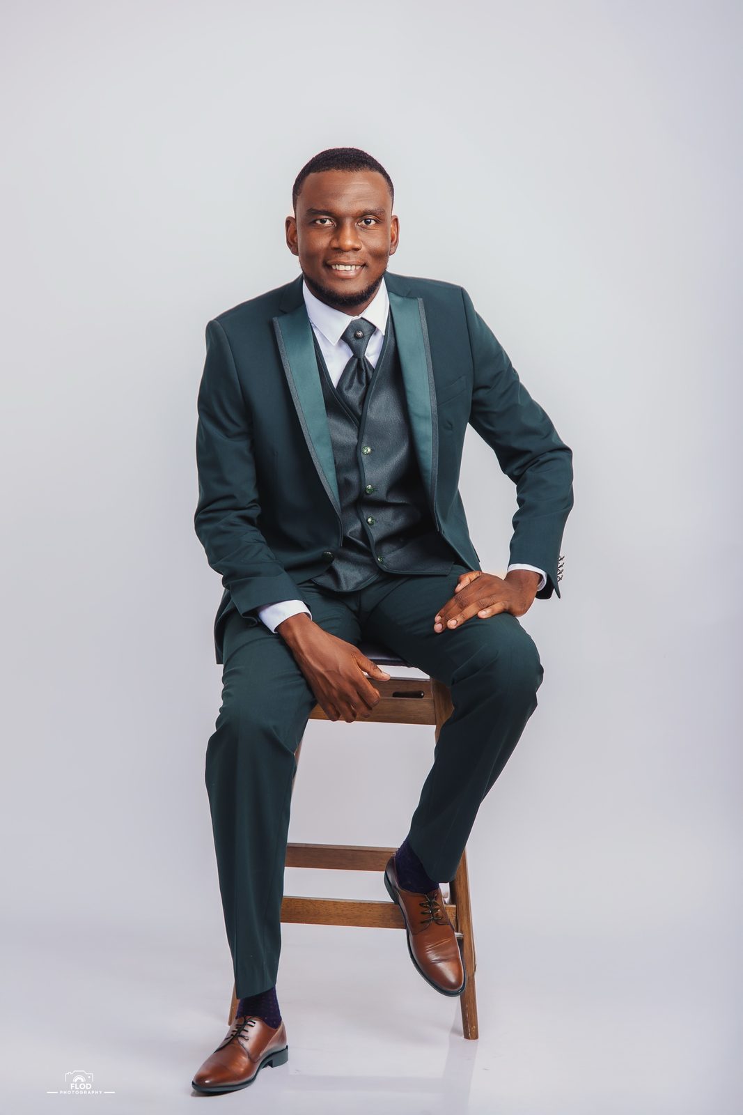 Portrait studio homme en costume vert trois pièces assis sur un tabouret