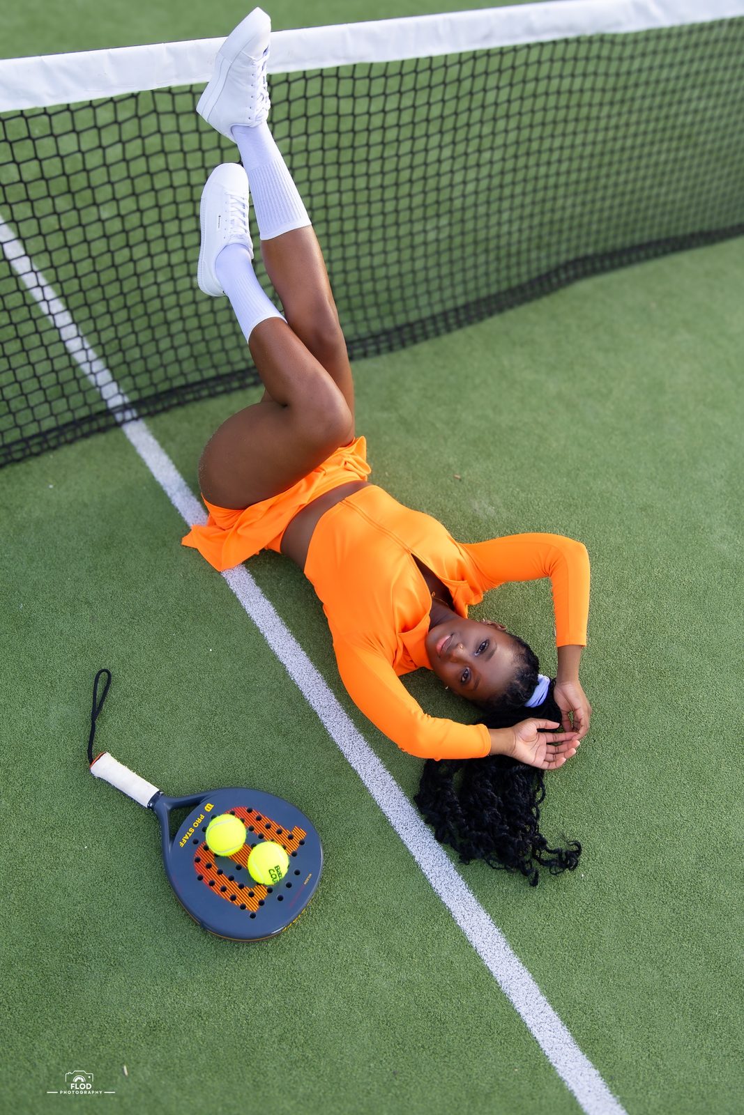 Portrait vu du dessus, tenue orange et raquette de padel sur le court