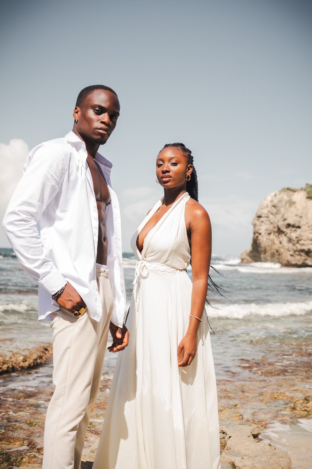 Couple en tenues blanches sur les rochers au bord de l'océan