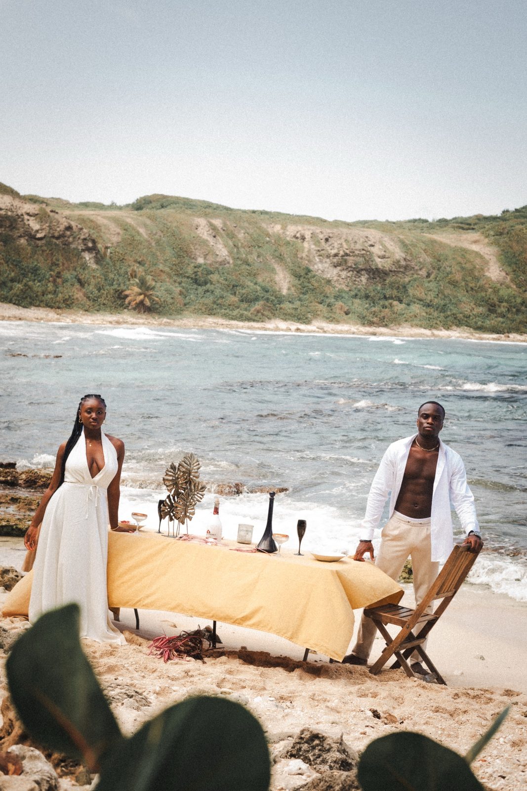 Couple autour d'une table dressée sur la plage, collines en fond