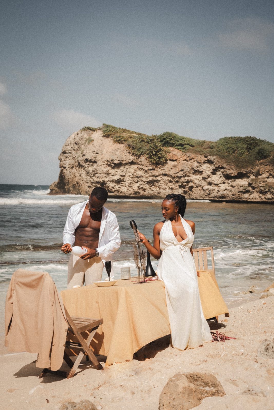 Couple complice servant un verre sur une table dressée à la plage