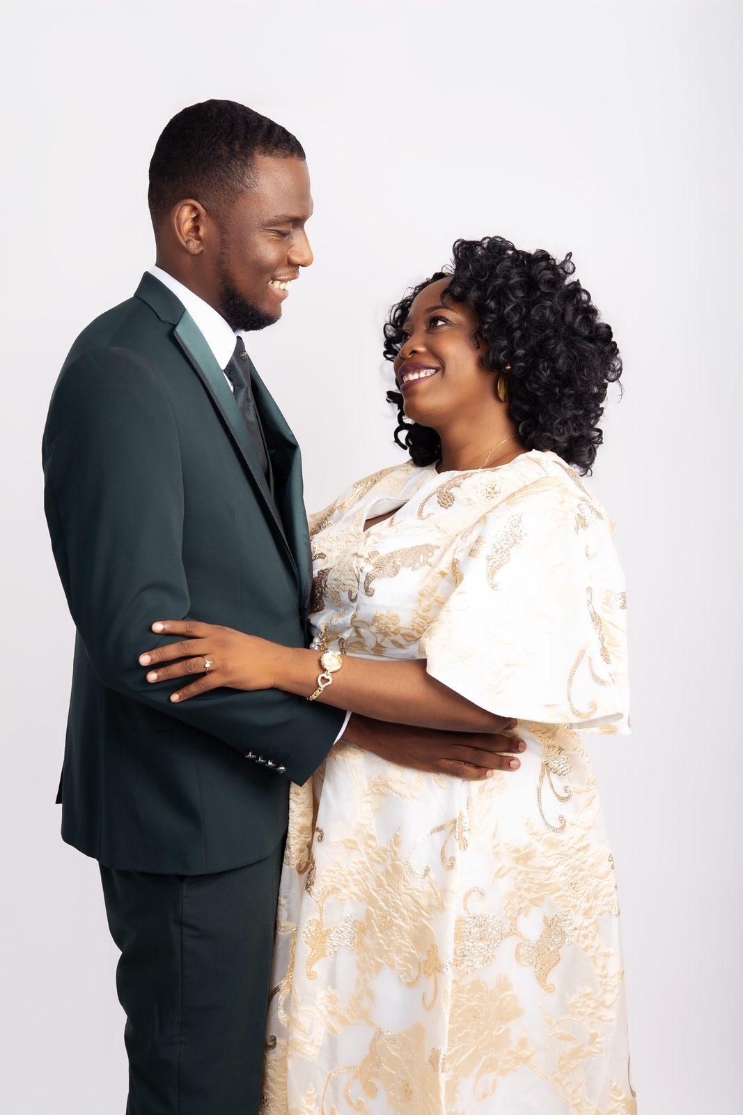 Couple complice en studio, costume vert et robe blanche et or, sourires