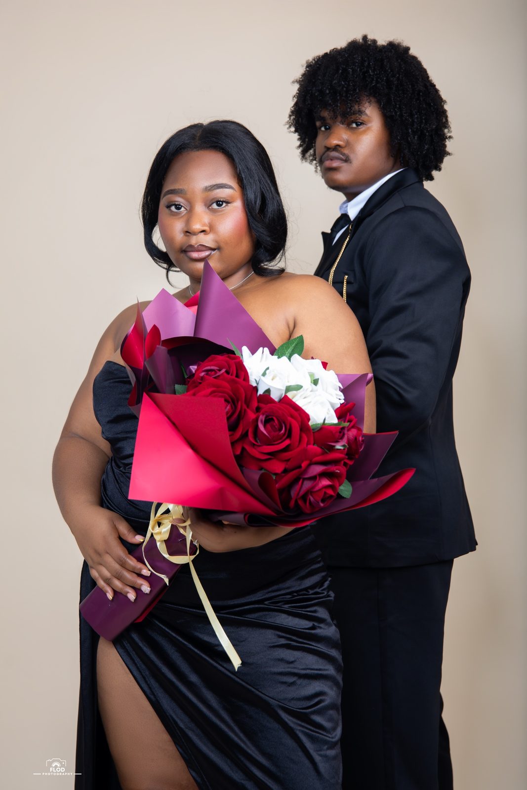 Couple en tenue de soirée noire avec un bouquet de roses rouges et blanches